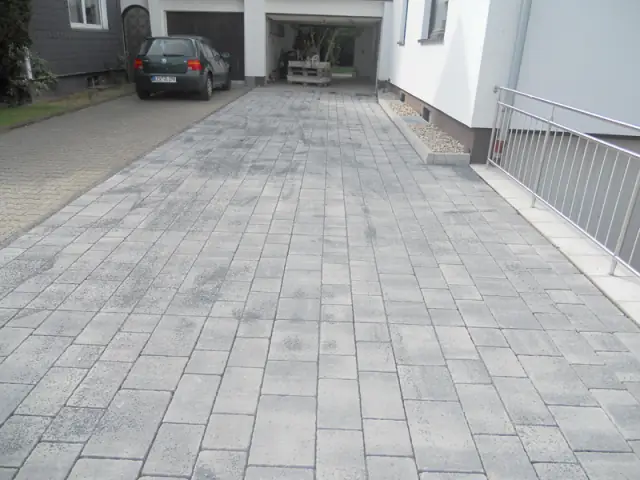 Gepflasterte Hofeinfahrt vor einem Wohnhaus mit Garage