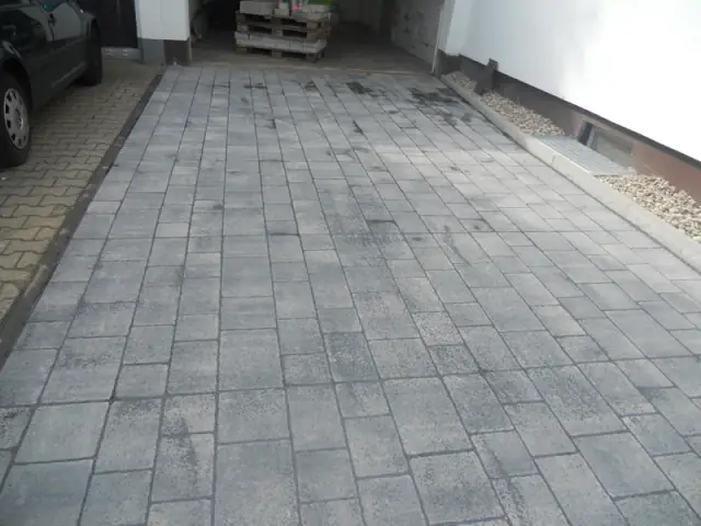 Zufahrt aus großformatigen Platten zwischen Haus und Garage