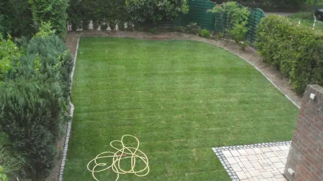 Fertig angelegter Garten: ebener Rasen mit geschwungener Kopfsteinkante