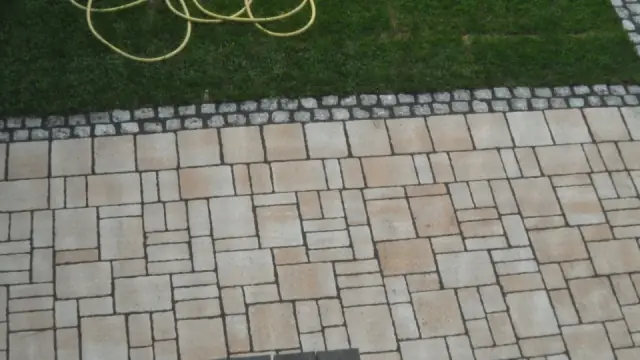 Übergang von Natursteinplatten zu Kopfsteinpflaster und Rasen