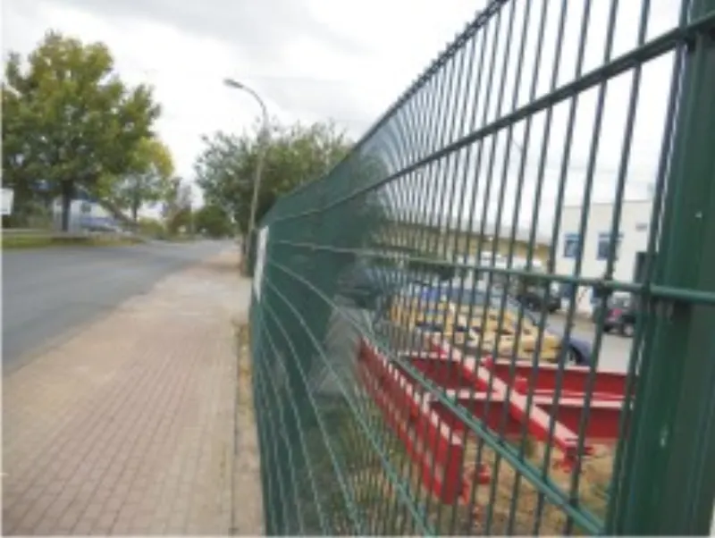 Grüner Gitterzaun entlang einer Straße